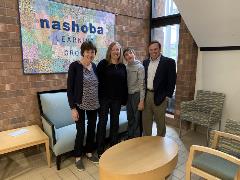 Liz Martineau, Michelle Arnold, Jack Thomas, and Justin Thomas pose in front of the Nashoba Learning Group display.